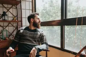 man sits in a chair and looks out the window