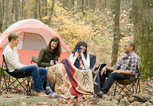 Group of friends laughing and talking while camping in the forest, enjoying nature with Good Friday Wellness Psilocybin Magic Mushrooms.