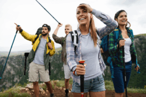Group of friends hiking on a mountain trail, smiling and exploring nature with trekking poles – Good Friday Wellness magic mushroom delivery.