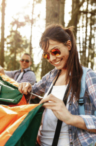 Woman smiling while pitching a colorful tent in the woods – Good Friday Wellness magic mushrooms