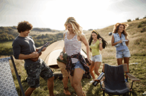 Group of friends dancing and playing music outdoors at a campsite – Good Friday Wellness magic mushrooms