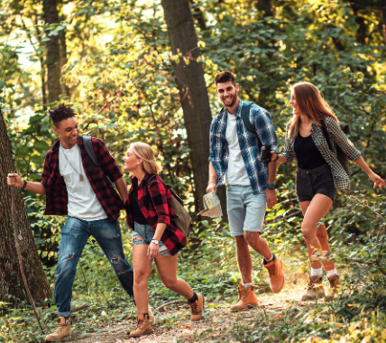 Group of friends hiking through a forest trail in casual plaid outfits