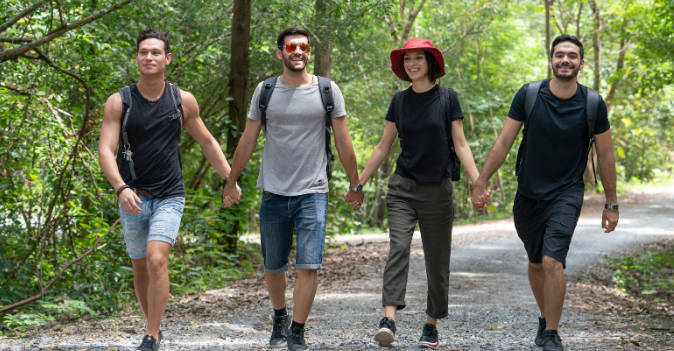 Group of happy hikers walking hand in hand through a forest trail, enjoying nature and community on a Good Friday Wellness magic mushrooms journey.