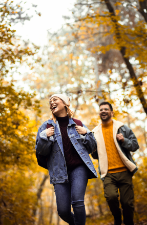 Couple hiking in autumn forest, smiling joyfully