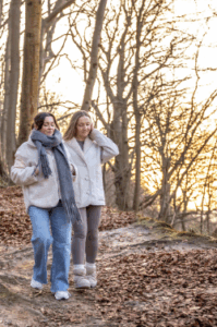 Two women walking forest trail at sunset
