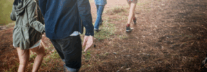 Group of hikers walking through a forest trail at sunset, representing a nature experience tied to Good Friday Wellness magic mushrooms.