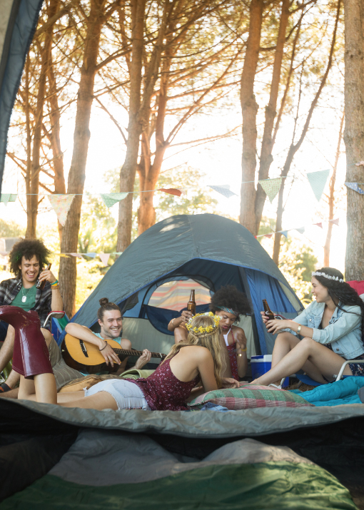 Group of friends camping and playing guitar, enjoying nature with Good Friday Wellness magic mushrooms
