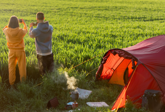 Couple enjoying nature and capturing the sunrise near a red tent while using Good Friday Wellness magic mushroom.