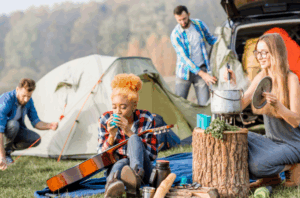 Group of friends camping, enjoying the outdoors with tents and guitars