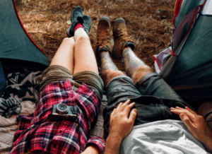 Couple relaxing in a tent at a forest campsite, capturing the moment, representing a peaceful vibe linked with Good Friday Wellness magic mushroom delivery.