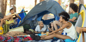 Group of friends camping with tents, smiling and relaxing outdoors.