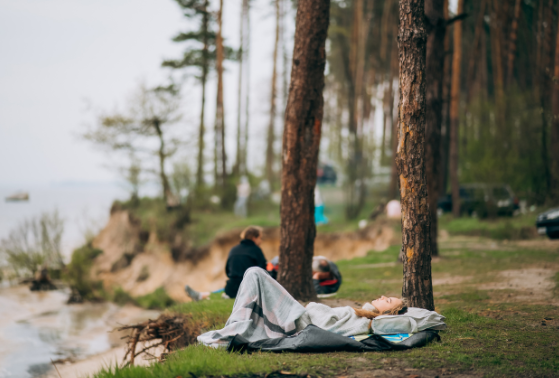 Couple relaxing in a forest campsite near a lake, enjoying nature and calm surroundings