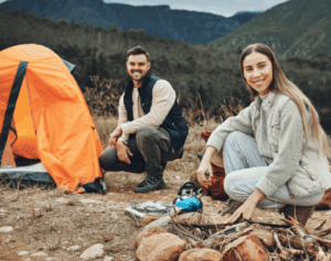 Smiling campers setting up a mountain campsite, supported by Good Friday Wellness magic mushroom capsules.