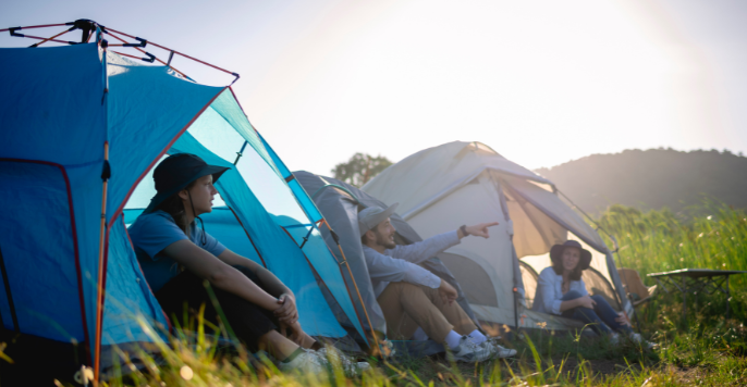 Group of campers relaxing beside their tents at sunset, enjoying nature