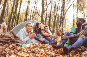 Group of friends camping and relaxing in fall forest setting – Good Friday Wellness magic mushroom delivery