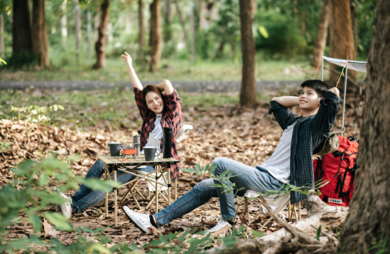 Couple relaxing at a forest campsite with red backpack and camp stove – Good Friday Wellness magic mushroom delivery