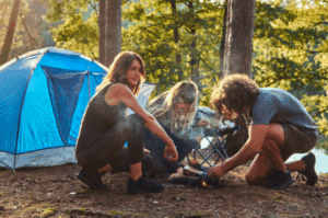Campers gathered around a fire preparing food.