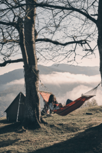 Couple resting in hammocks under tree with scenic mountains, embodying Good Friday Wellness Psilocybin Magic Mushrooms vibe.