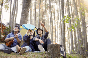 Friends sitting in a forest with binoculars and a ukulele, birdwatching and enjoying nature – Good Friday Wellness magic mushroom delivery.