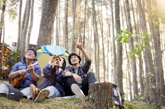 Friends sitting in a forest with binoculars and a ukulele, birdwatching and enjoying nature – Good Friday Wellness magic mushroom delivery.