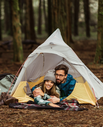 Couple relaxing inside a tent during a forest camping trip.