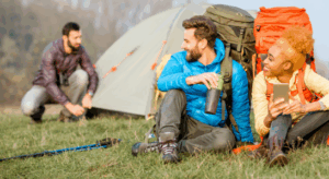 People relaxing on a vibrant camping mat near colorful tents, enjoying the outdoors—ideal for a Good Friday Wellness magic mushroom capsules moment.