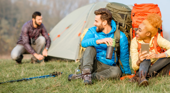 People relaxing on a vibrant camping mat near colorful tents, enjoying the outdoors—ideal for a Good Friday Wellness magic mushroom capsules moment.