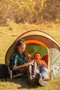 Couple relaxing in a small camping tent outdoors, symbolizing nature-focused wellness and tranquility.
