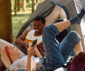 Couple enjoying the outdoors near their tent, smiling and relaxing together.